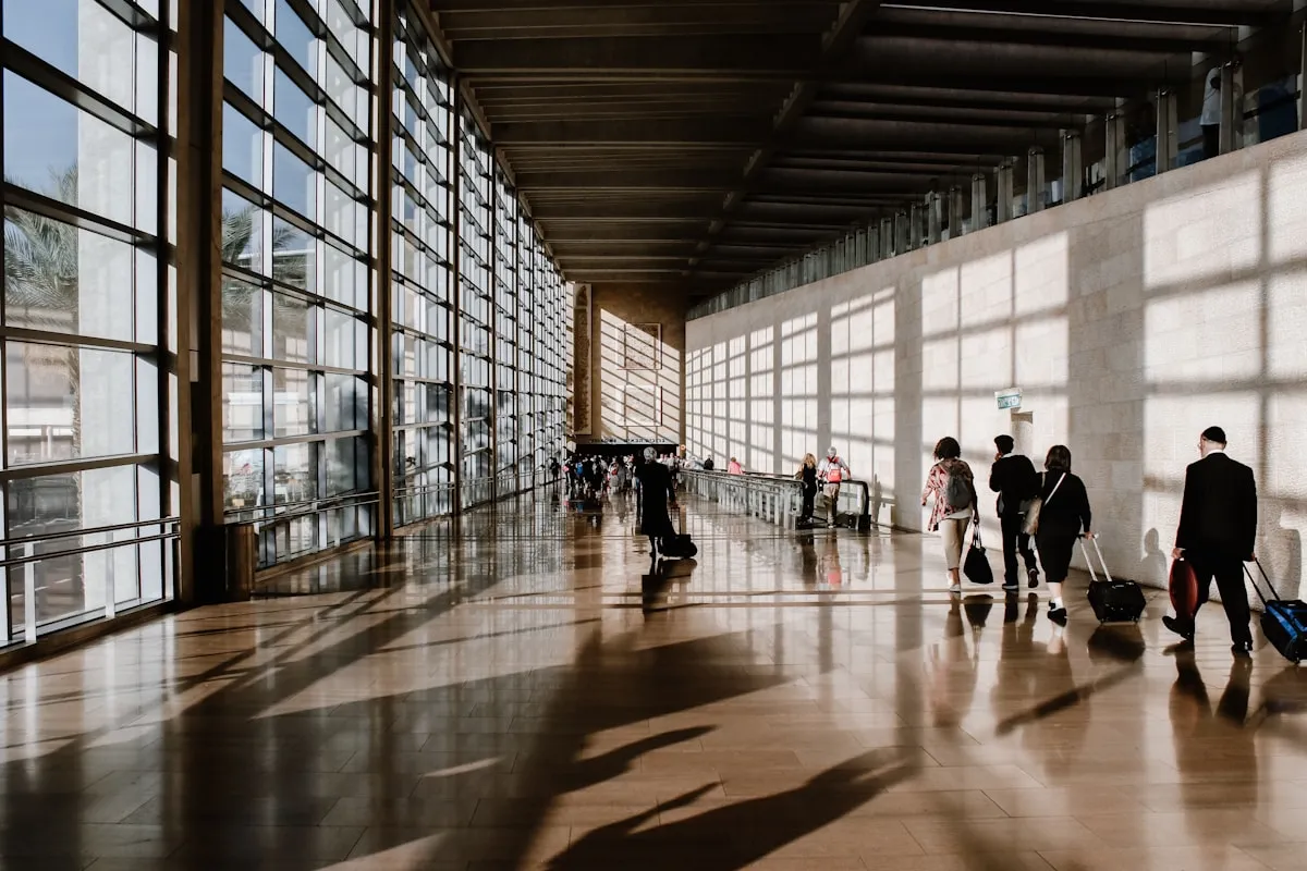 Travellers with luggage moving through a bright airport terminal