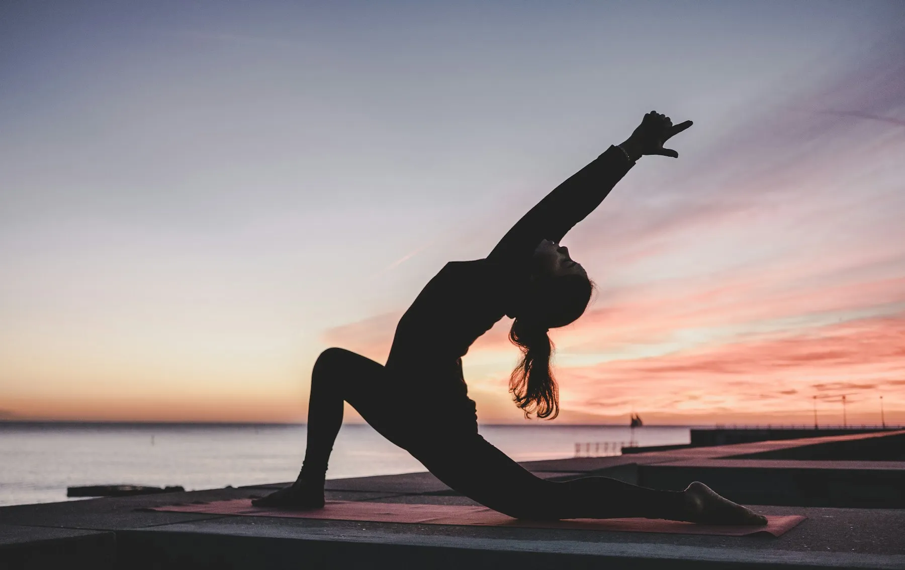 Traveller practising yoga beside the sea at sunrise
